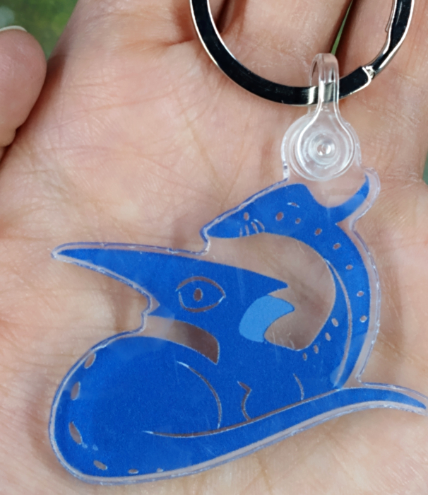 picture of a blue dragon keychain held in the palm of a pale hand.